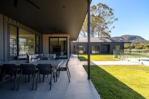 Un patio con una mesa y sillas en una casa. en Chris' II, Designer Masterpiece in Kangaroo Valley, en Valle Kangaroo