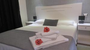 Una cama blanca con toallas y flores rojas. en Arts & Rooms, en Roma