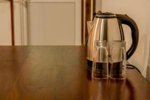 a tea kettle and two glasses on a wooden table at Shan Resort in Gintota
