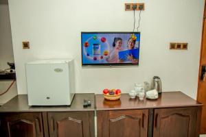a kitchen counter with a refrigerator and a tv on the wall at Shan Resort in Gintota