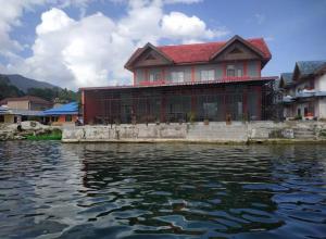 a large red house sitting on top of a body of water at Vila tujutake in Parapat