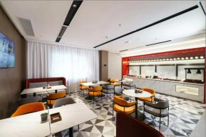 Un restaurante con mesas y sillas y una cocina. en Parkman Hotel Guangzhou Pazhou Convention and Exhibition Center Luntou Branch, en Guangzhou