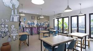 ein Restaurant mit Tischen und Stühlen und Graffiti an der Wand in der Unterkunft Casa Living Setiabudi Jakarta in Jakarta