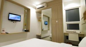 ein Schlafzimmer mit einem Bett, einem Fernseher und einem Spiegel in der Unterkunft Casa Living Setiabudi Jakarta in Jakarta