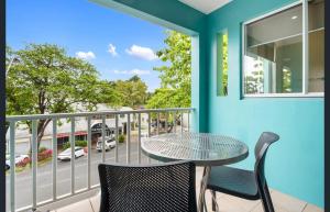 Coconut Palms - In the Heart of Port Douglas & Near the Beach في ميناء دوغلاس: بلكونه فيها طاوله وكراسي وشارع +صورتان