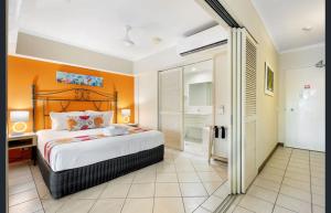 Coconut Palms - In the Heart of Port Douglas & Near the Beach في ميناء دوغلاس: غرفة نوم بسرير بحائط برتقالي