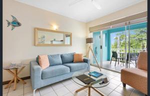Coconut Palms - In the Heart of Port Douglas & Near the Beach في ميناء دوغلاس: غرفة معيشة مع أريكة زرقاء وطاولة