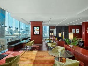 Un vestíbulo de un hotel con mesas y sillas. en ibis Kuwait Salmiya, en Kuwait