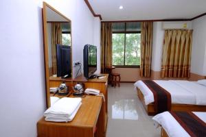 ein Hotelzimmer mit zwei Betten und einem Fernseher in der Unterkunft PC Palace Hotel in Sakon Nakhon