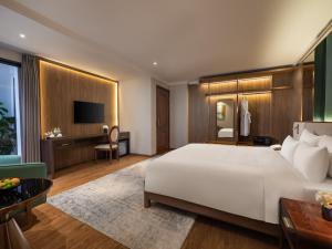 a bedroom with a large white bed and a tv at Splendid Secret Hotel in Hanoi