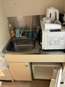 a kitchen counter with a sink and a microwave at SJins in Tokyo