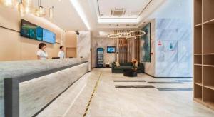 eine Lobby eines Hotels mit zwei Personen, die an einem Tresen stehen in der Unterkunft City Comfort Inn Zhongshan Lihe Square Walmart Branch in Zhongshan