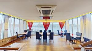 EXIGEHOME-Large houseboat with spa near Paris في سان-كلو: مطعم به طاولات وكراسي ونوافذ كبيرة