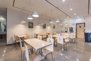un ristorante con tavoli e sedie in una stanza di 7 Days Premium Jinan Gaoxin Qu Wanda Plaza a Jinan