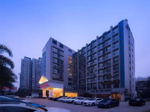 zwei hohe Gebäude mit Autos auf einem Parkplatz in der Unterkunft Vienna Hotel Chengdu Chunxi Road Lijiatuo Metro Station in Chengdu