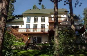 a large white house with a balcony and trees at River Cove Elegant Waterfront Bed & Breakfast in Post Falls