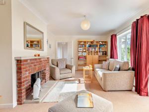 4 Bed in Studland 75639 في ستودلاند: غرفة معيشة مع موقد من الطوب وستائر حمراء