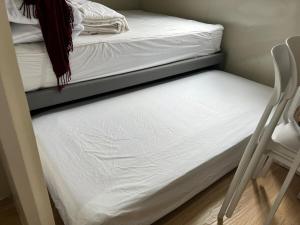 Stylish Container House in Tagaytay - The Manger في Kaybagal: سرير بطابقين مع مرتبة بيضاء وكرسي