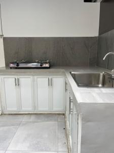 Stylish Container House in Tagaytay - The Manger في Kaybagal: مطبخ بخزائن بيضاء ومغسلة +5 صور