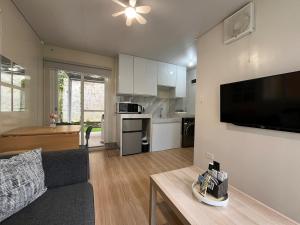 Stylish Container House in Tagaytay - The Manger في Kaybagal: غرفة معيشة بها أريكة وتلفزيون على الحائط