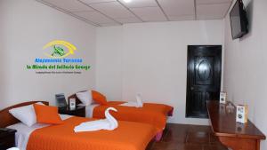 two beds in a room with two swans on them at Hostal La Mirada del Solitario George in Puerto Ayora