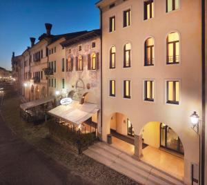 una vista esterna di un edificio con tavoli e sedie di Hotel Canon d'Oro a Conegliano