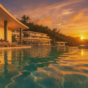 ein Resortpool mit Sonnenuntergang im Hintergrund in der Unterkunft The View Kata Karon in Kata Beach