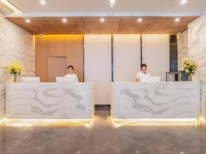 zwei Personen an Schreibtischen in einem Zimmer mit Laptops in der Unterkunft VX Hotel Xiamen Siming District Xiamen University Huandao Road in Xiamen