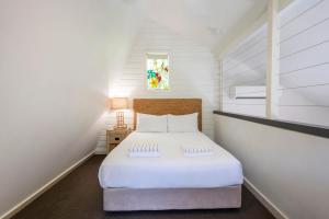 een kleine slaapkamer met een wit bed op een zolder bij Bayshore Bungalow 3 - Oceanstays in Byron Bay