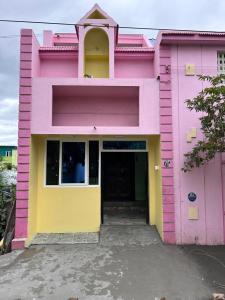 ein rosa und gelbes Gebäude mit einer Tür in der Unterkunft CR Residency in Tiruvannāmalai