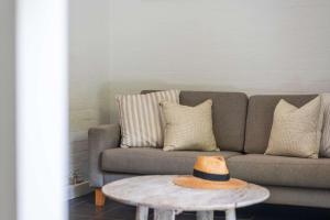 Bayshore Bungalow 2 - Oceanstays في خليج بايرون: غرفة معيشة مع أريكة وقبعة على طاولة