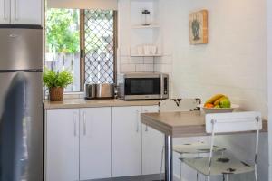 Bayshore Bungalow 2 - Oceanstays في خليج بايرون: مطبخ مع دواليب بيضاء وطاولة مع ميكروويف