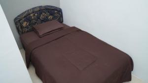 Bett in einem Zimmer mit brauner Tagesdecke in der Unterkunft Rumah Penataran Syariah in Blimbing + 2 Fotos