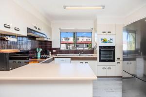 a white kitchen with a sink and a stove at Esplanade Charm Apartment in Torquay +33 photos