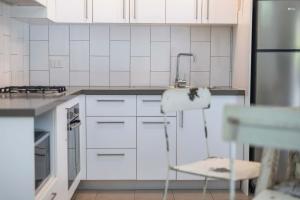 Bayshore Bungalow 5 - Oceanstays في خليج بايرون: مطبخ بدولاب بيضاء ومغسلة وكرسي