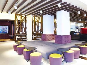 a room with purple and yellow stools and a table at Novotel London Brentford in Brentford