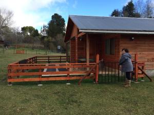 una mujer parada frente a una cabaña de madera en Rancho Saeta, en Villarrica