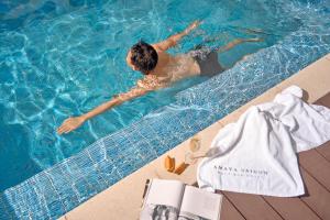 a man is swimming in a swimming pool at Amaya Saigon Boutique Hotel in Ho Chi Minh City