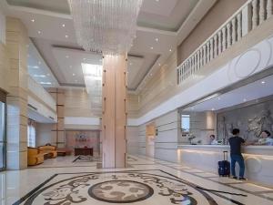 Ein Mann steht in einer Lobby mit einem Koffer. in der Unterkunft Vienna Hotel Nanning Anji Wanda 33rd Middle School Metro Station in Nanning