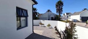 SerenShell House في Stompneusbaai: بيت ابيض به سياج ابيض وبيوت