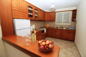 a kitchen with a bowl of apples and a bottle of wine at Palman Othonoi House in Othonoi +11 photos