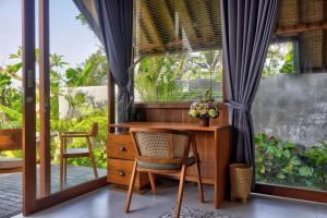 een bureau en stoel in een kamer met een raam bij The Udiana Ubud in Ubud