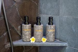 een groep van drie flessen op een plank met bloemen bij The Udiana Ubud in Ubud +38 foto's