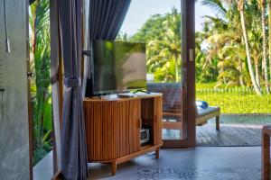 a flat screen tv sitting on a stand in a room at The Udiana Ubud in Tegalalang