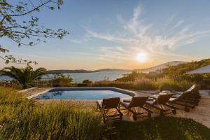 a pool with chairs and a view of the water at Villa Amarina in Trogir