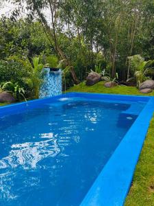 a blue swimming pool with grass and trees in the background at Cozy haven in Auroville