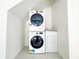 a washing machine and a dryer in a room at Brand-New 5BR Retreat, Space & Serenity by Nature in Auckland