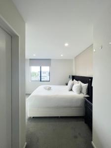 a bedroom with a large white bed with a window at Brand-New 5BR Retreat, Space & Serenity by Nature in Auckland