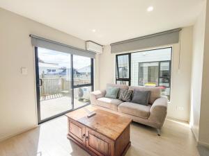 a living room with a couch and a coffee table at Brand-New 5BR Retreat, Space & Serenity by Nature in Auckland