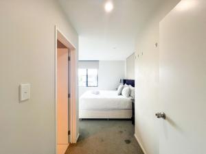 a white bedroom with a bed and a hallway at Brand-New 5BR Retreat, Space & Serenity by Nature in Auckland